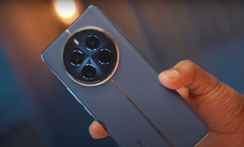 Close-up of a person holding a black Realme 12 Pro Plus 5G smartphone. The phone has a large screen and a triple-lens rear camera.